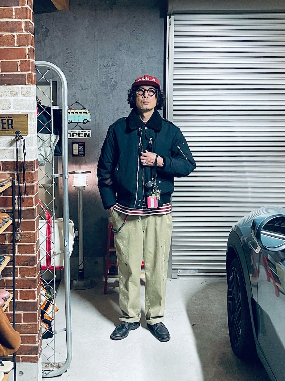 レッド系のTシャツ/カットソー、グリーン系のバックパック/リュック、ブラック系のミリタリージャケットを着用したメンズの冬コーディネートの2枚目の写真