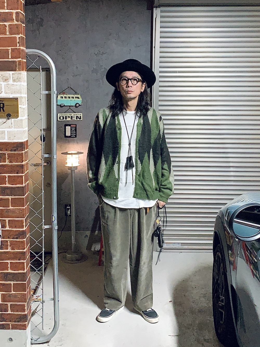 ベージュ系のその他パンツ、ブラック系のスニーカー、グリーン系のカーディガン/ボレロを着用したメンズの秋コーディネートの2枚目の写真