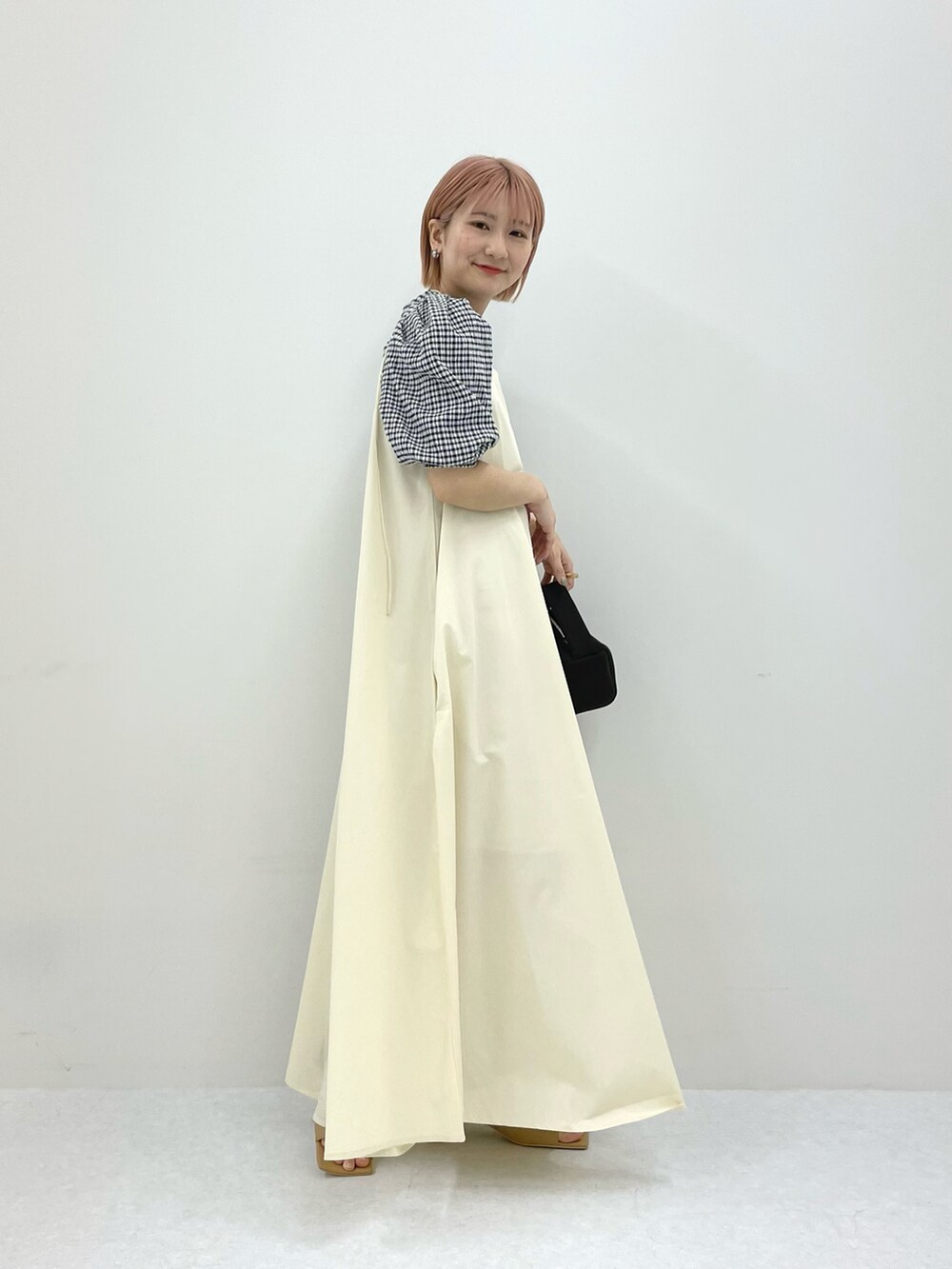 ホワイト系のワンピース、ブラウン系のハンドバッグ、ブラック系のシャツ/ブラウスを着用したレディースの春コーディネートの2枚目の写真