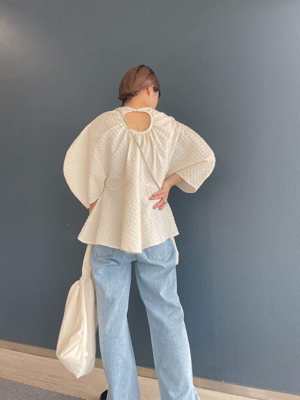 ブルー系のデニムパンツ、ホワイト系のシャツ/ブラウス、ホワイト系のショルダーバッグを着用したレディースの夏コーディネートの2枚目の写真