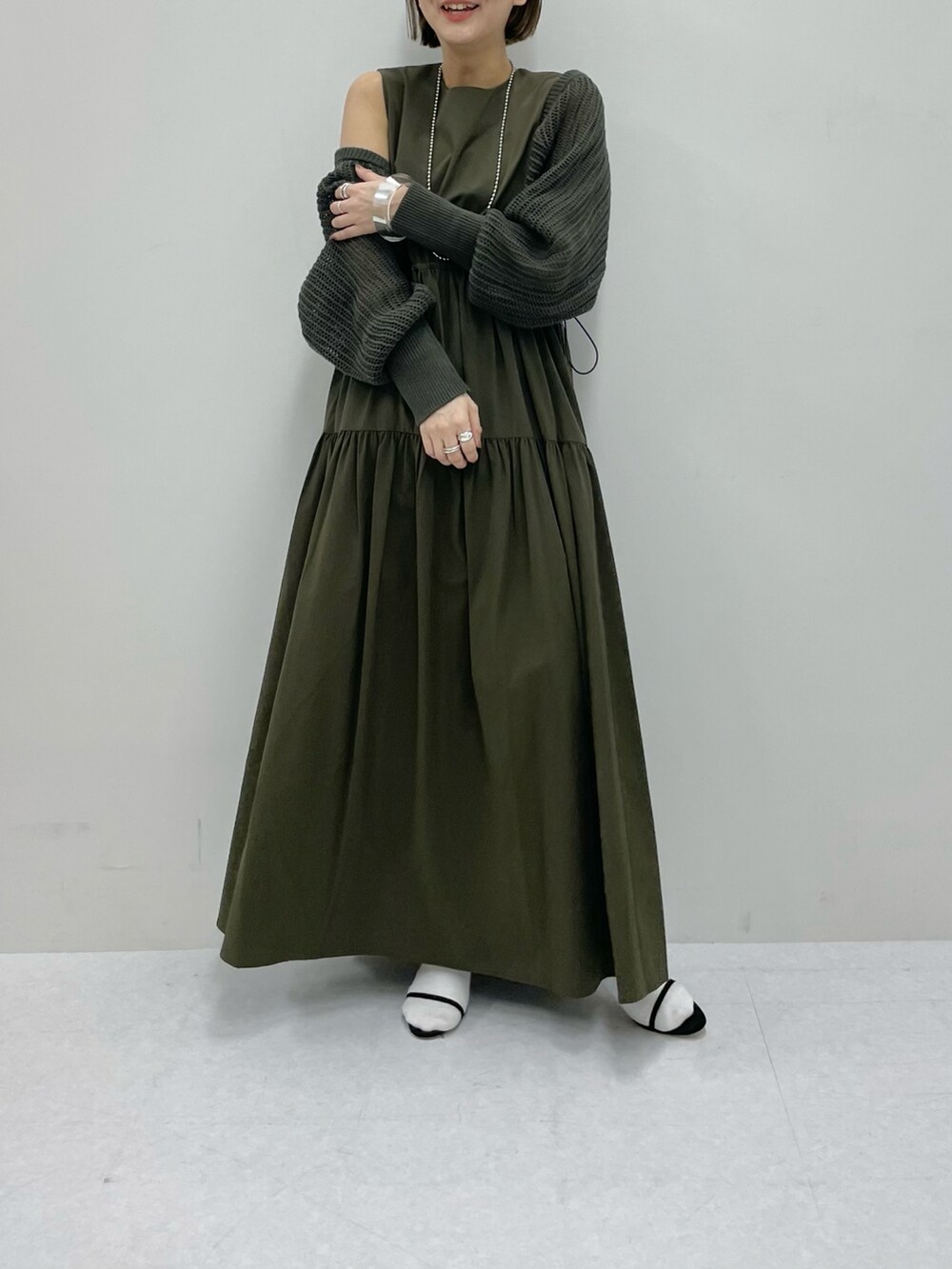 グリーン系のベスト、ブラック系のサンダル、グリーン系のワンピースを着用したレディースの春コーディネートの2枚目の写真