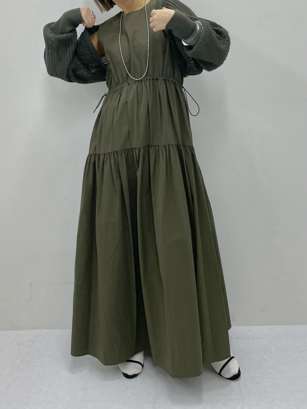 グリーン系のベスト、ブラック系のサンダル、グリーン系のワンピースを着用したレディースの春コーディネートの3枚目の写真