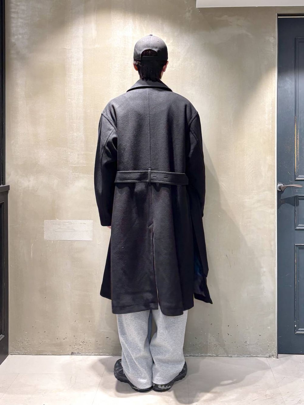 ブラック系のトレンチコート、グレー系のスウェットパンツ、ブラック系のニット/セーターを着用したメンズの冬コーディネートの3枚目の写真