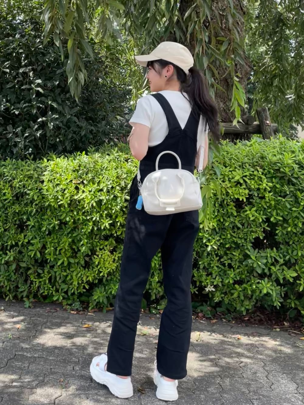 ホワイト系のサンダル、ブラック系のサロペット/オーバーオール、ホワイト系のTシャツ/カットソーを着用したレディースの秋コーディネートの2枚目の写真