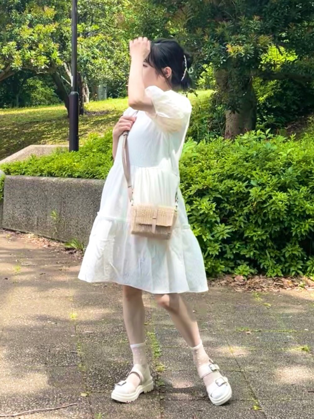 ホワイト系のワンピース、ベージュ系のショルダーバッグ、ホワイト系のサンダルを着用したレディースの夏コーディネートの2枚目の写真