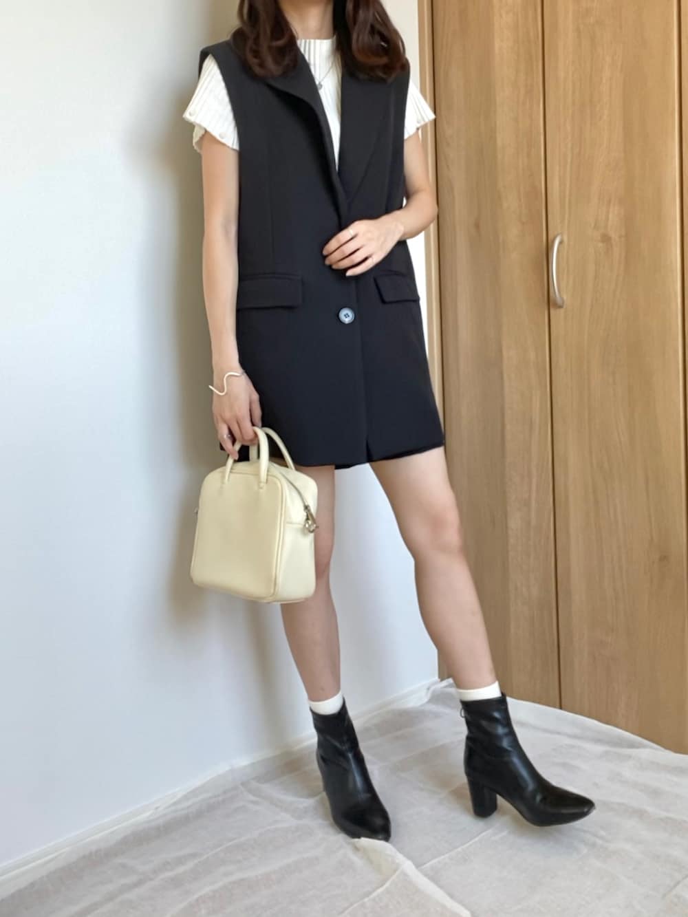 ホワイト系のニット/セーター、ブラック系のセットアップ、ベージュ系のバッグを着用したレディースの夏コーディネートの2枚目の写真