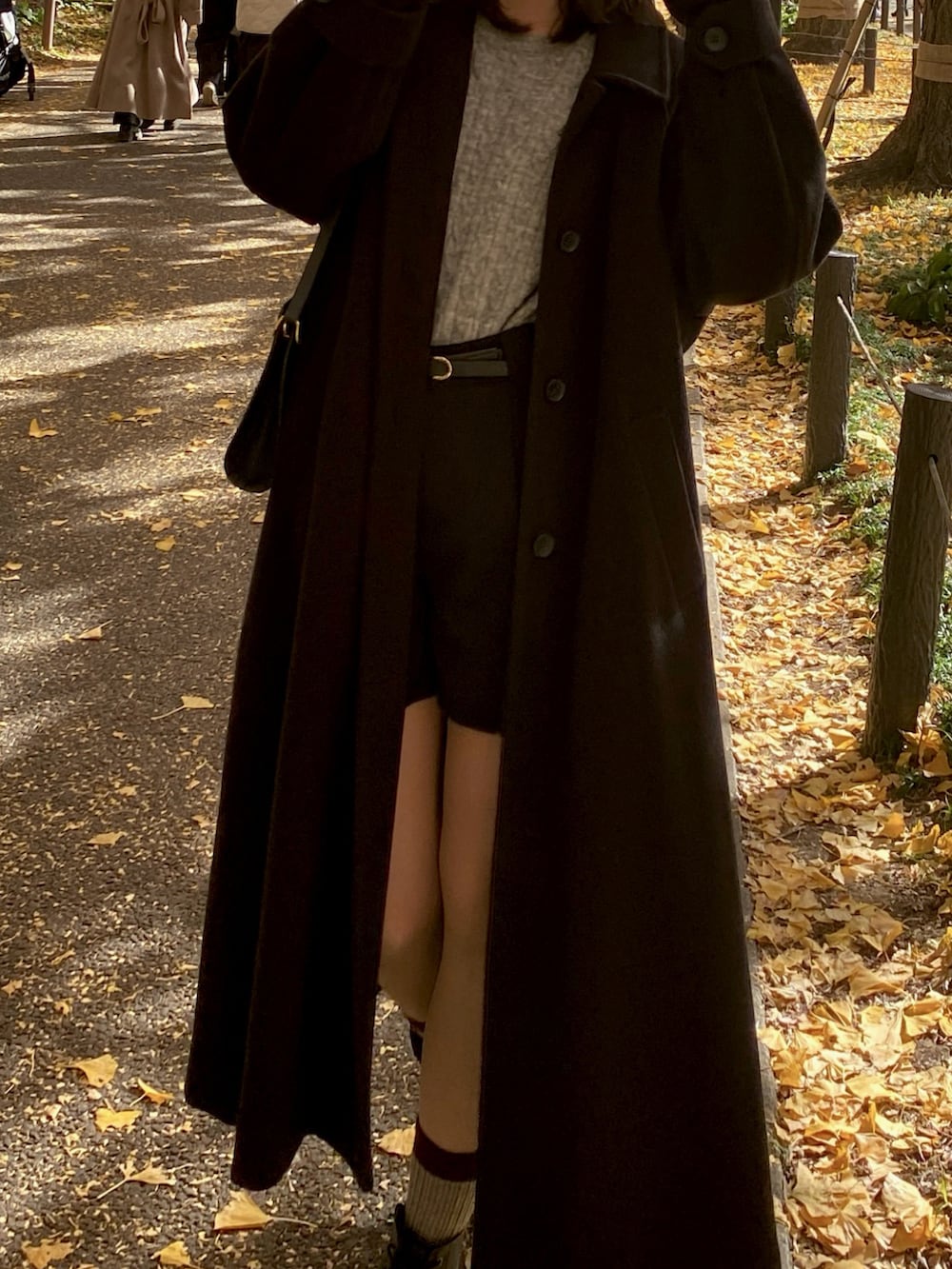 グレー系のニット/セーター、ブラック系のステンカラーコート、ブラック系のその他パンツを着用したレディースの冬コーディネートの2枚目の写真