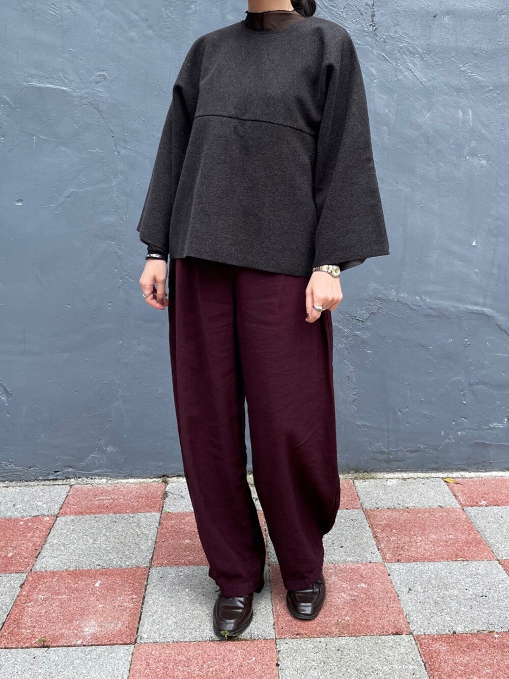 レッド系のその他パンツ、グレー系のポンチョ、グレー系のその他トップスを着用したレディースの冬コーディネートの2枚目の写真