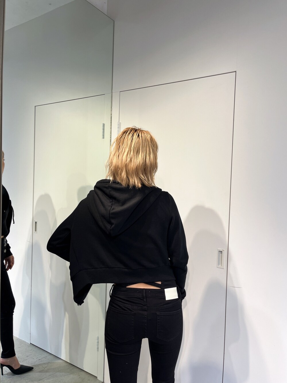 ブラック系のデニムパンツ、ブラック系のパーカー、ブラック系のキャミソールを着用したレディースの春コーディネートの6枚目の写真