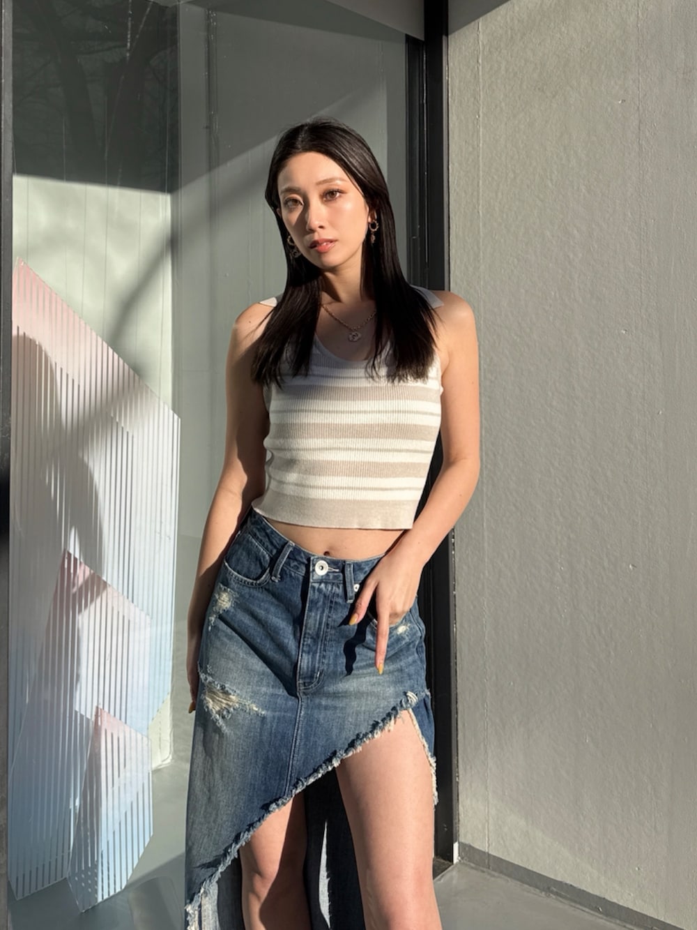 ブルー系のデニムスカート、ベージュ系のニット/セーターを着用したレディースの夏コーディネートの5枚目の写真