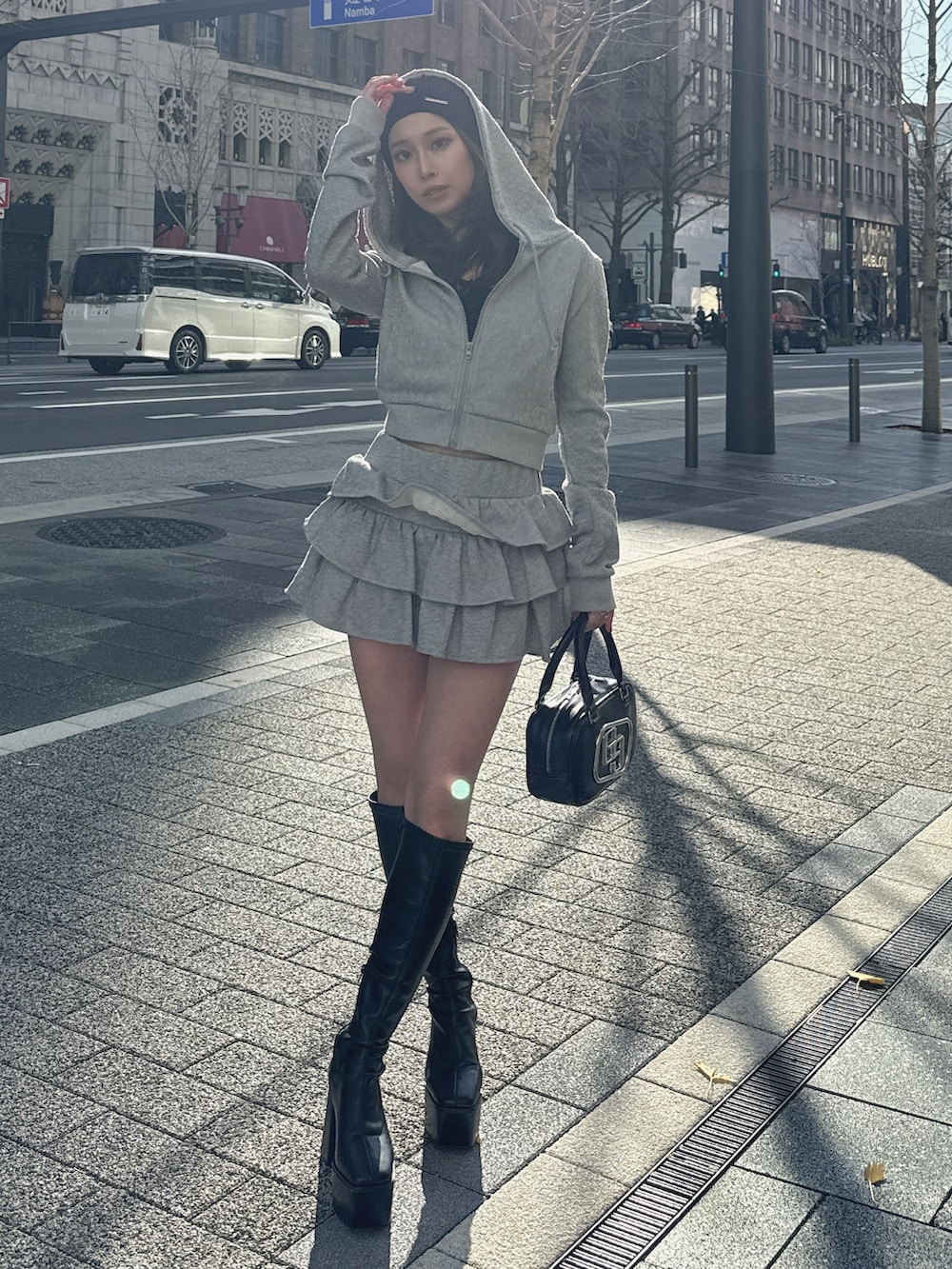 グレー系のパーカー、グレー系のスカート、ブラック系のブーツを着用したレディースの冬コーディネートの3枚目の写真