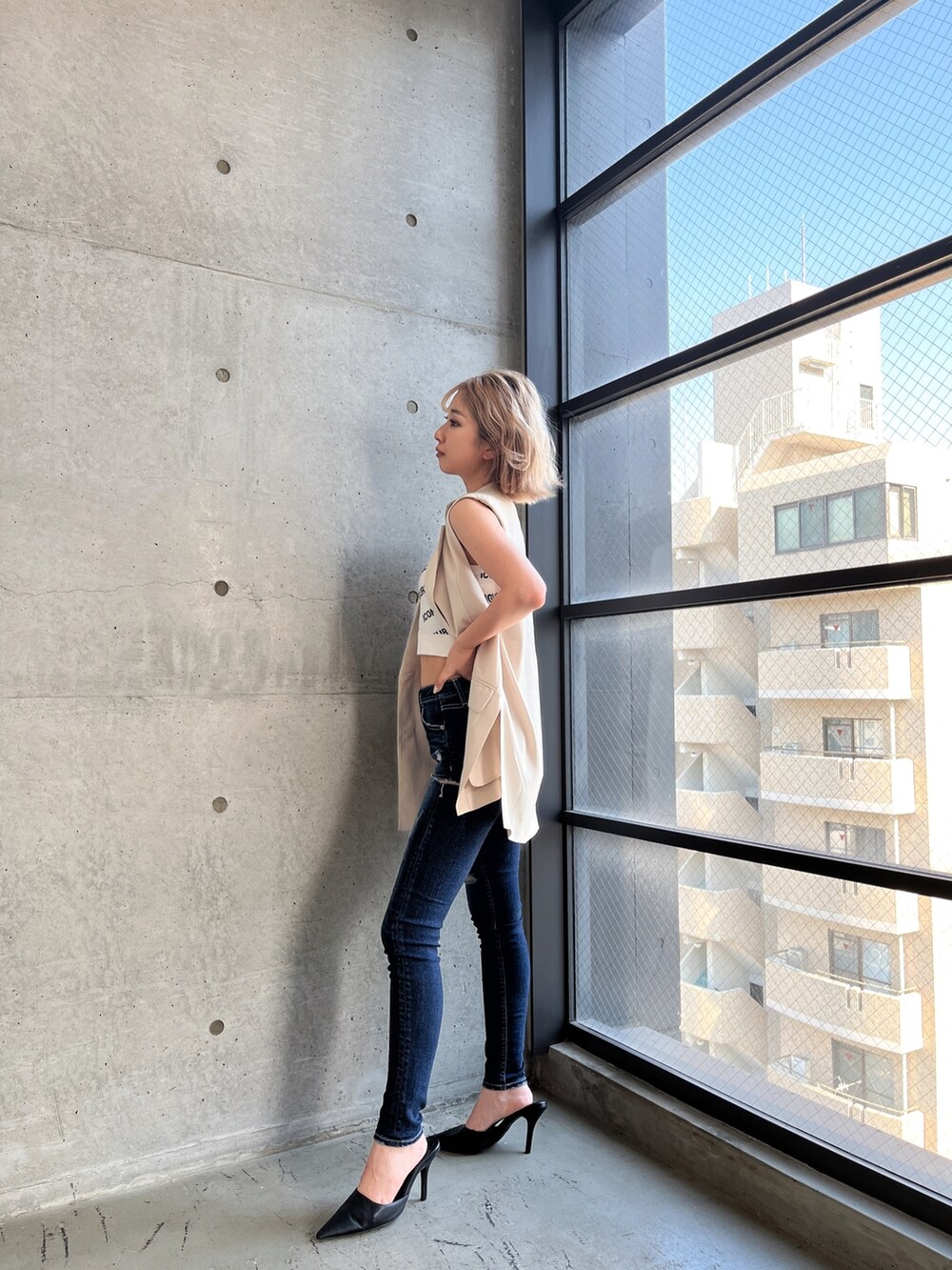 ホワイト系のニット/セーター、ブルー系のデニムパンツ、ホワイト系のテーラードジャケットを着用したレディースの夏コーディネートの2枚目の写真