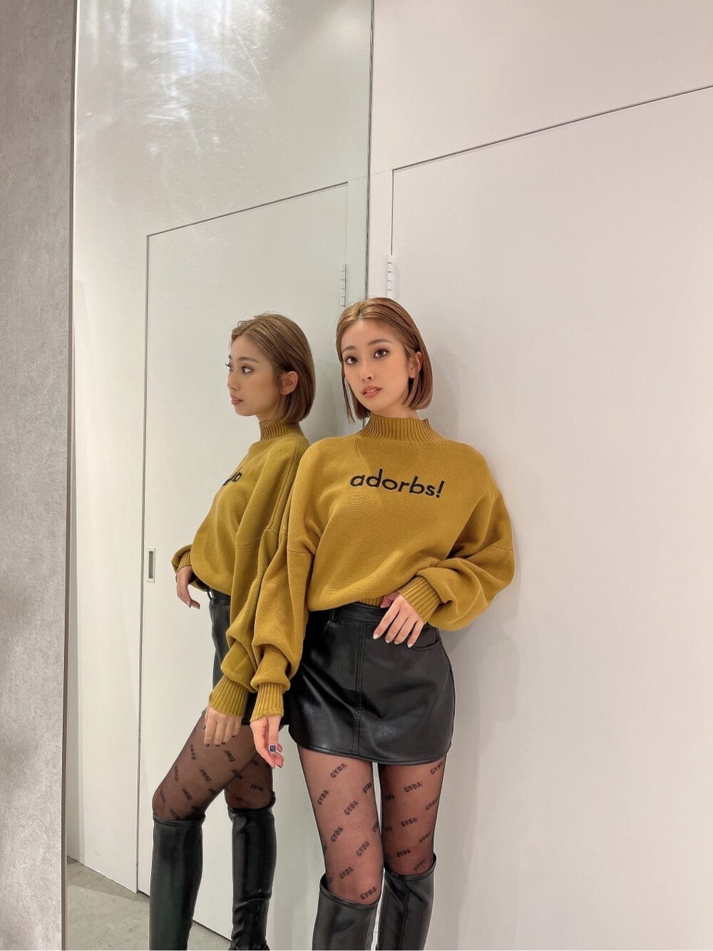 ブラック系のブーツ、イエロー系のニット/セーター、ブラック系のスカートを着用したレディースの秋コーディネートの4枚目の写真