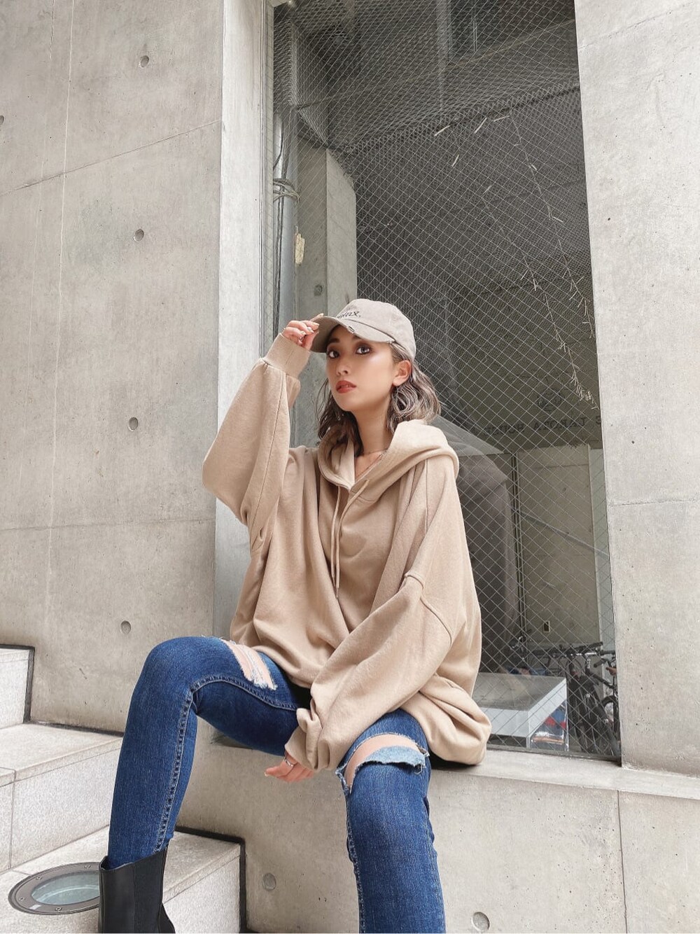 ブルー系のデニムパンツ、ベージュ系のパーカー、ベージュ系のキャップを着用したレディースの秋コーディネートの5枚目の写真