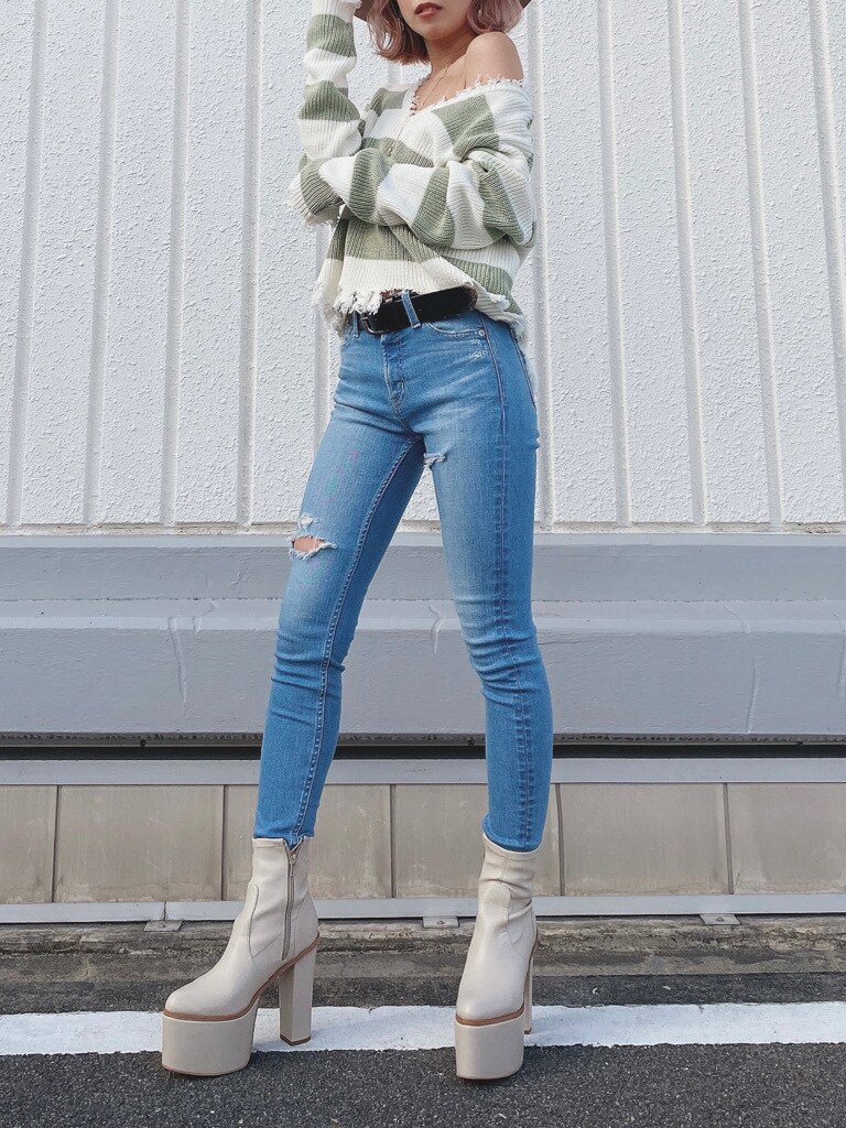 グリーン系のニット/セーター、ホワイト系のブーツ、ブルー系のデニムパンツを着用したレディースの冬コーディネートの2枚目の写真