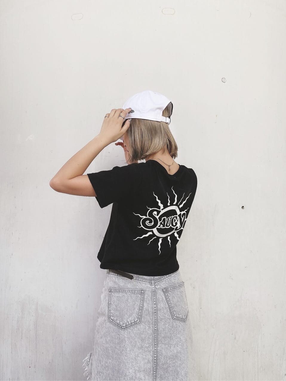 グレー系のデニムスカート、ブラック系のTシャツ/カットソー、ブラック系のパンプスを着用したレディースの夏コーディネートの4枚目の写真