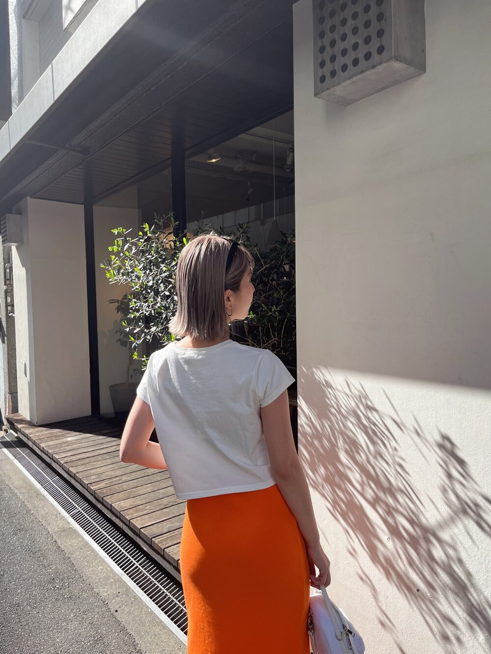 ホワイト系のTシャツ/カットソー、オレンジ系のスカートを着用したレディースの春コーディネートの7枚目の写真