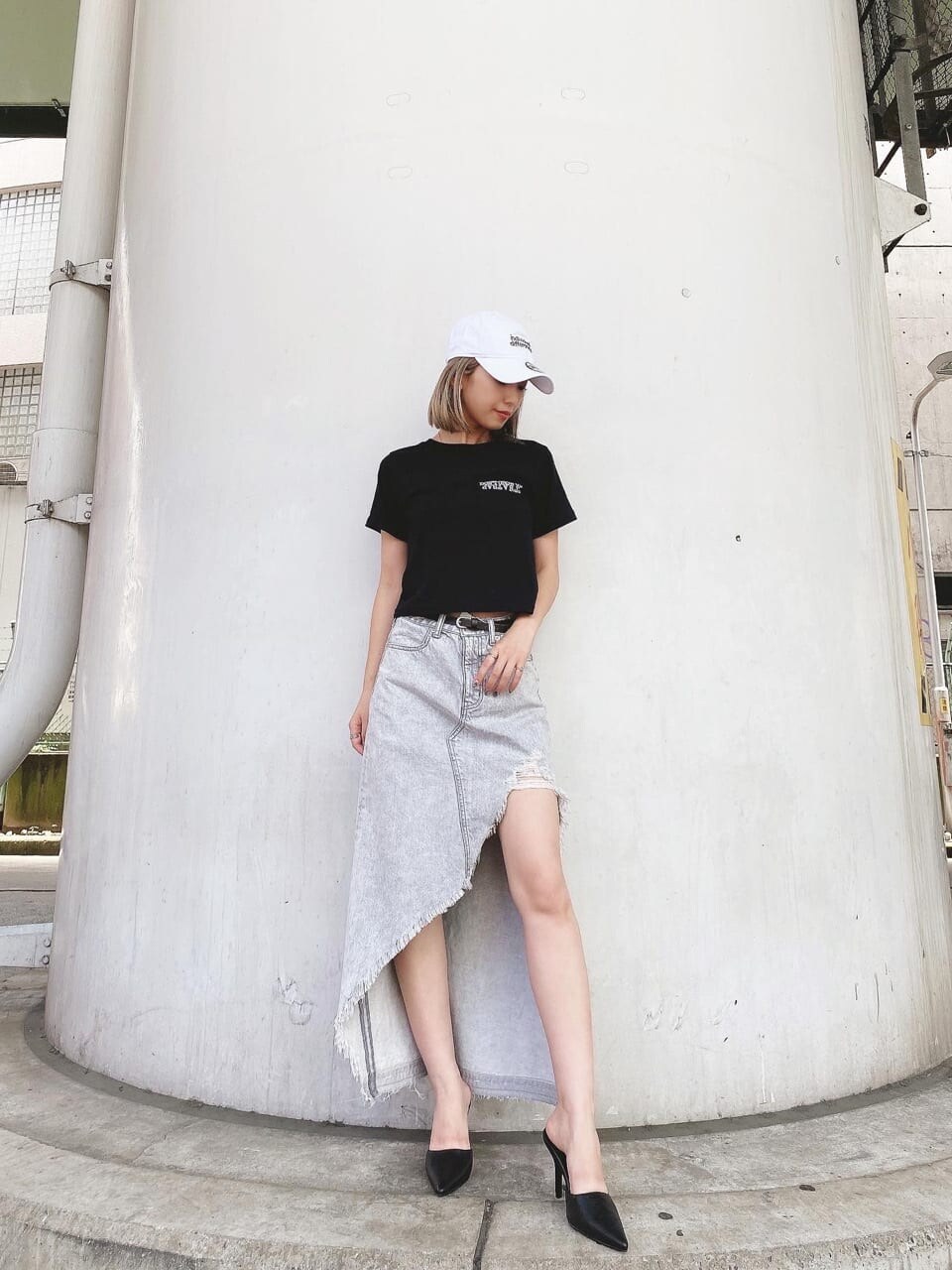 グレー系のデニムスカート、ブラック系のTシャツ/カットソー、ブラック系のパンプスを着用したレディースの夏コーディネートの2枚目の写真