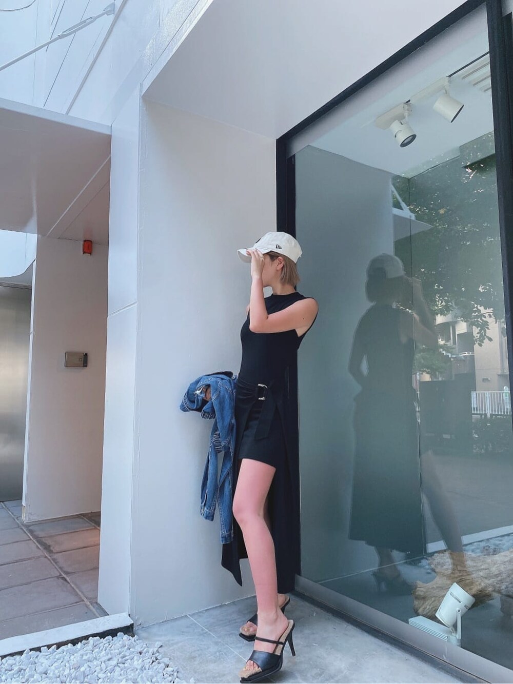 ブラック系のワンピース、ブラック系のサンダル、ホワイト系のキャップを着用したレディースの夏コーディネートの4枚目の写真