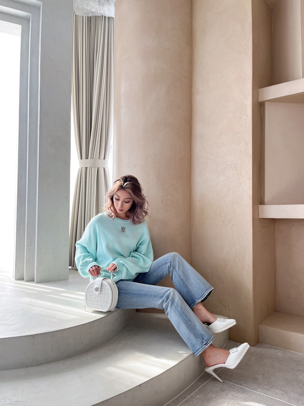 グリーン系のニット/セーター、ブルー系のデニムパンツ、ホワイト系のハンドバッグを着用したレディースの冬コーディネートの3枚目の写真