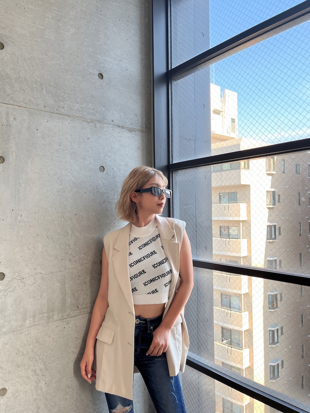 ホワイト系のニット/セーター、ブルー系のデニムパンツ、ホワイト系のテーラードジャケットを着用したレディースの夏コーディネートの4枚目の写真