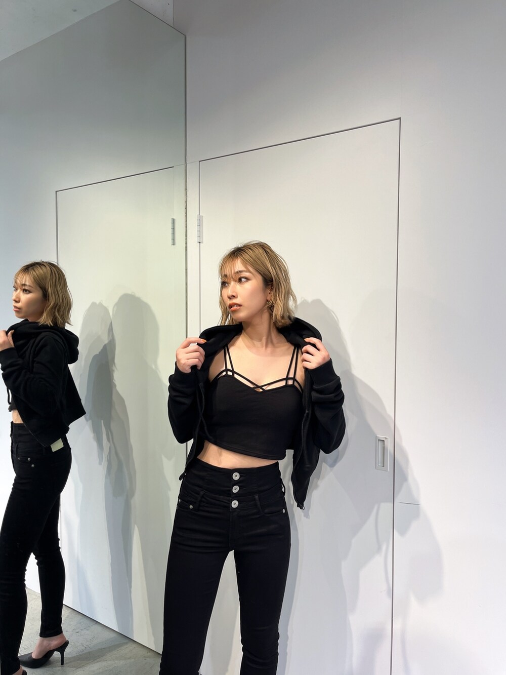 ブラック系のデニムパンツ、ブラック系のパーカー、ブラック系のキャミソールを着用したレディースの春コーディネートの8枚目の写真
