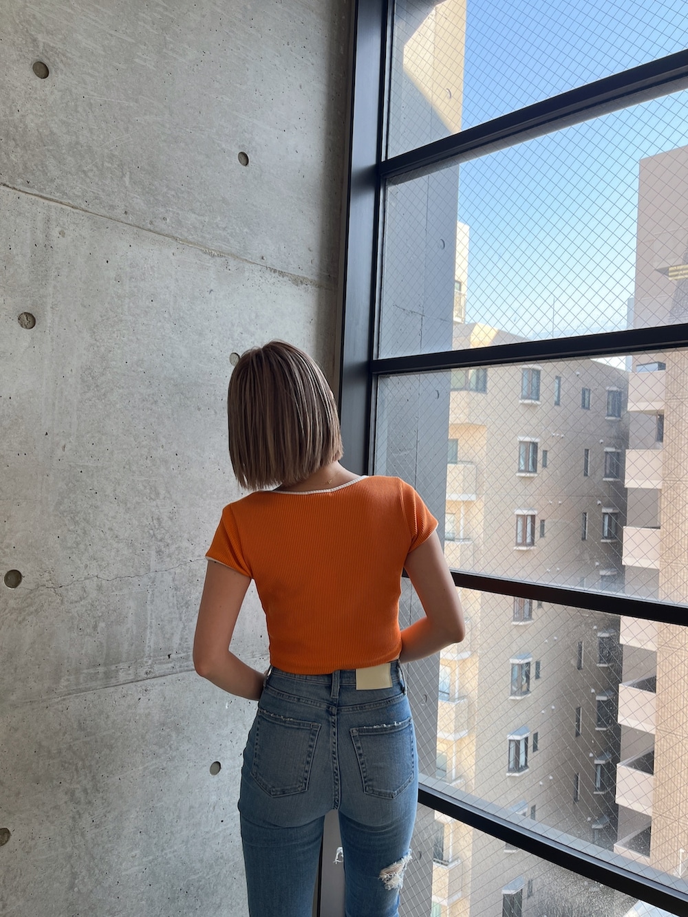 オレンジ系のTシャツ/カットソーを着用したレディースの春コーディネートの3枚目の写真