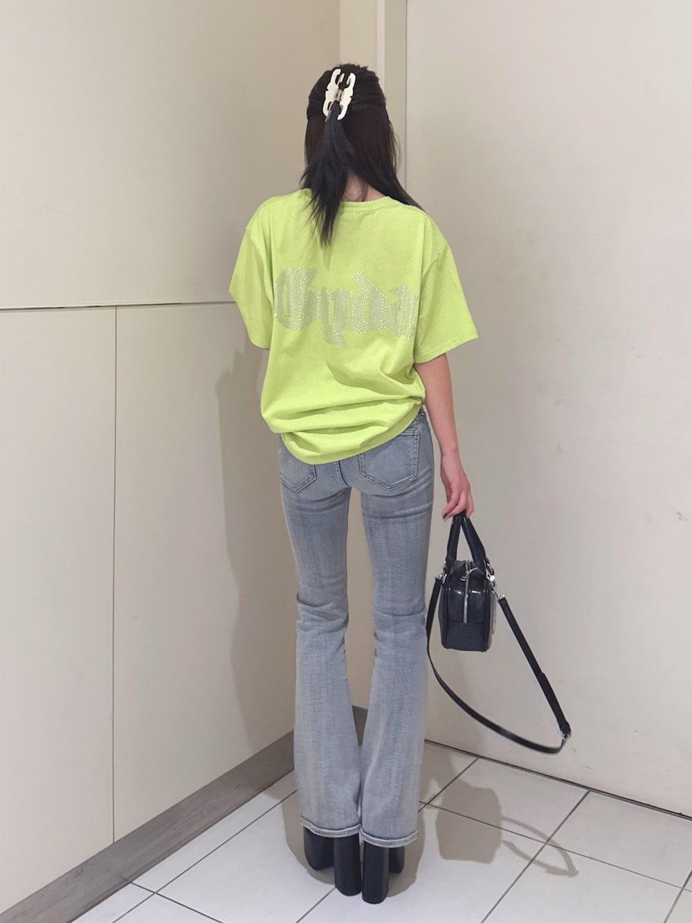 ブルー系のデニムパンツ、ブラック系のサンダル、ブラック系のハンドバッグを着用したレディースの夏コーディネートの3枚目の写真