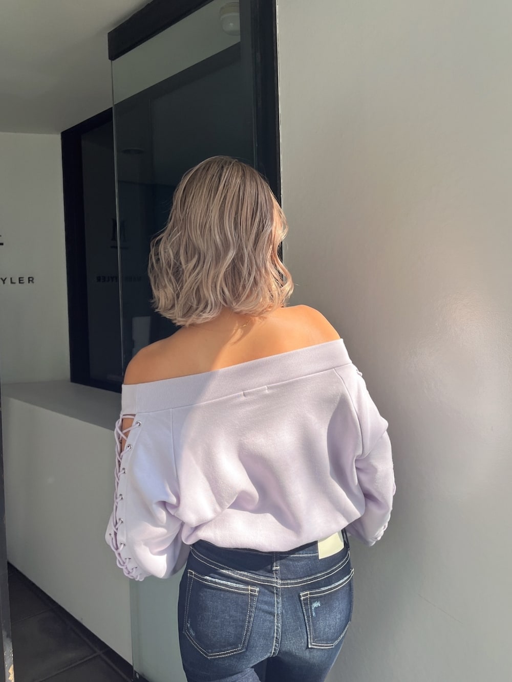 パープル系のスウェット、ブルー系のデニムパンツを着用したレディースの春コーディネートの2枚目の写真