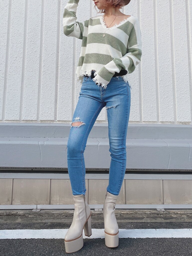 グリーン系のニット/セーター、ホワイト系のブーツ、ブルー系のデニムパンツを着用したレディースの冬コーディネートの3枚目の写真