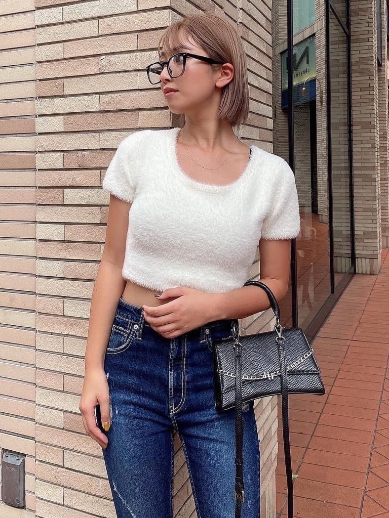 ブルー系のデニムパンツ、ブラック系のハンドバッグ、ブラック系のブーツを着用したレディースの夏コーディネートの2枚目の写真