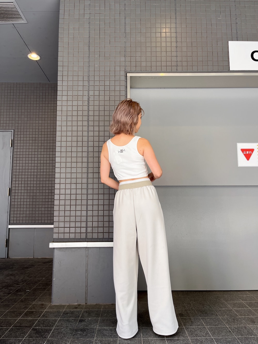 ホワイト系のタンクトップ、ホワイト系のスウェットパンツ、ホワイト系のパンプスを着用したレディースの夏コーディネートの2枚目の写真