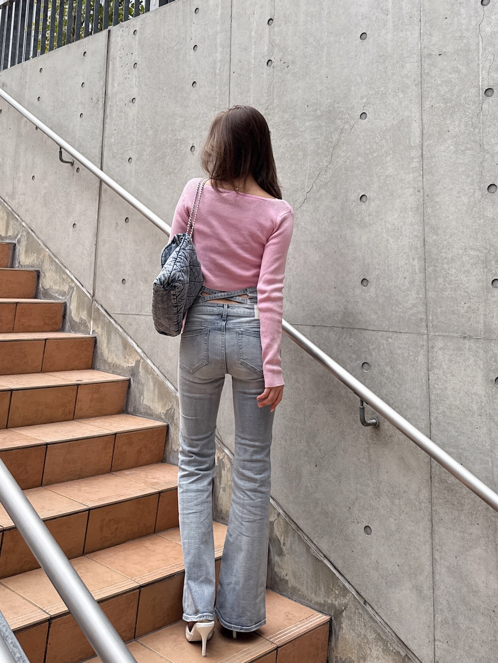 ブルー系のデニムパンツ、ピンク系のニット/セーターを着用したレディースの春コーディネートの2枚目の写真