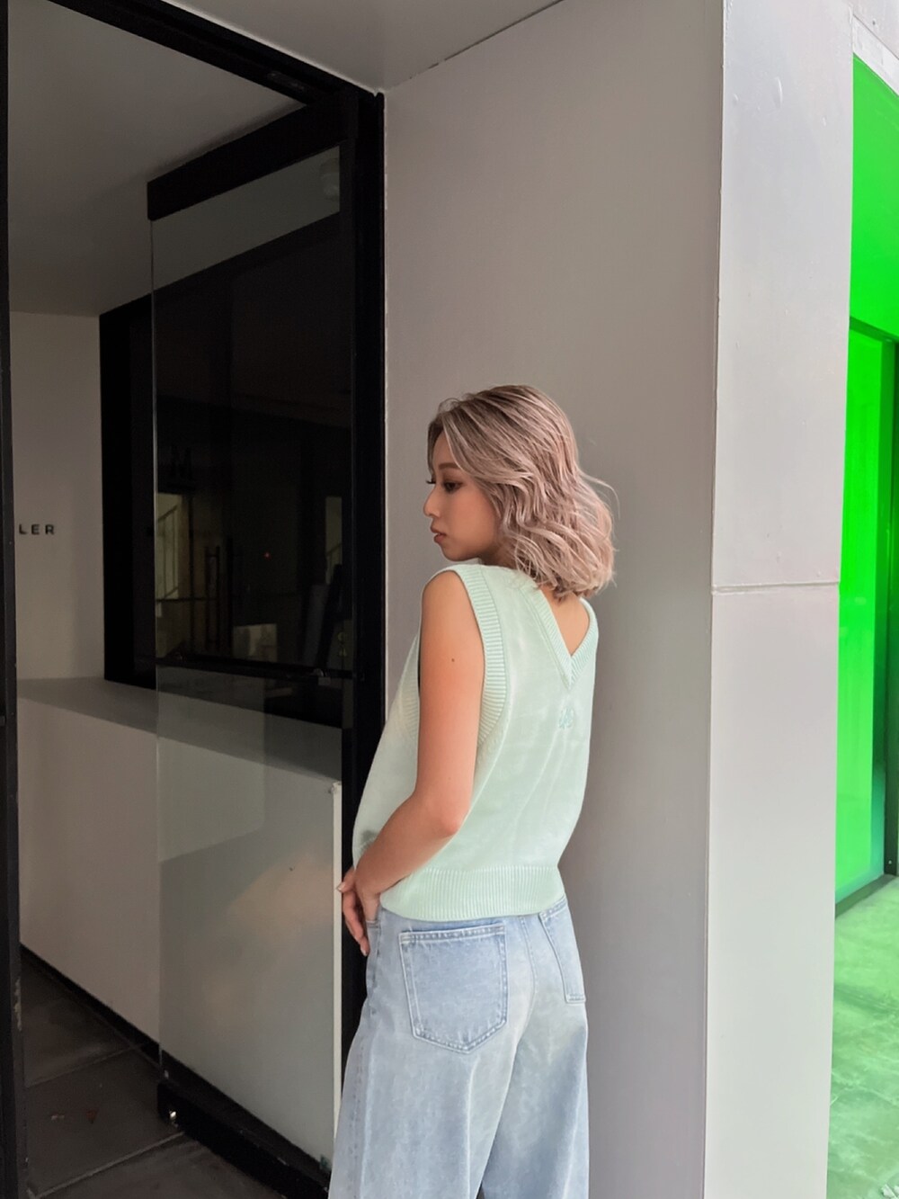 グリーン系のベスト、ブルー系のデニムパンツを着用したレディースの春コーディネートの3枚目の写真
