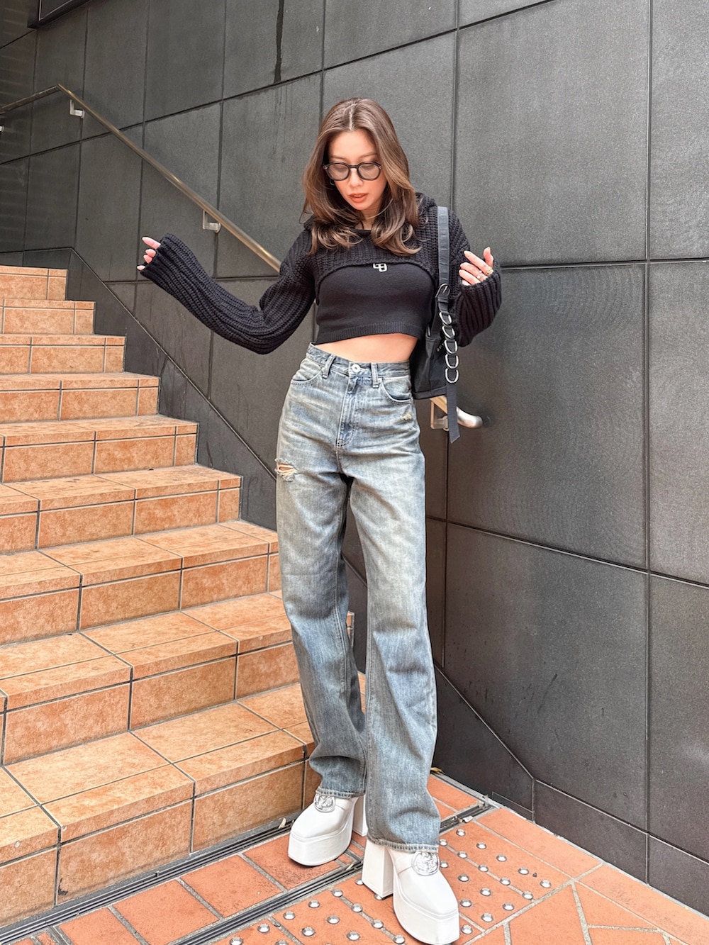 ブルー系のデニムパンツ、ブラック系のニット/セーターを着用したレディースの春コーディネートの2枚目の写真