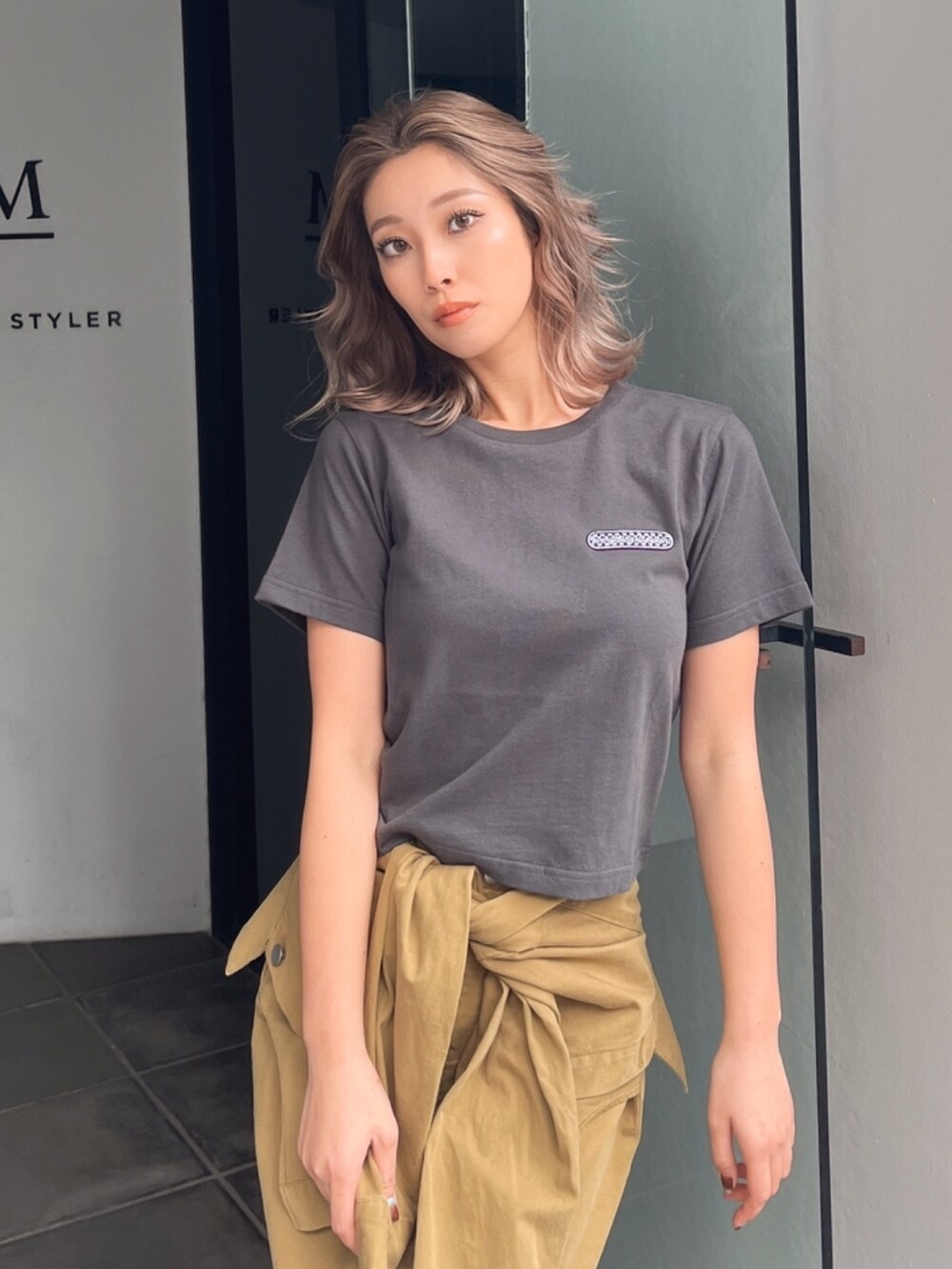 グレー系のTシャツ/カットソー、グリーン系のスカート、ブラック系のサンダルを着用したレディースの秋コーディネートの4枚目の写真