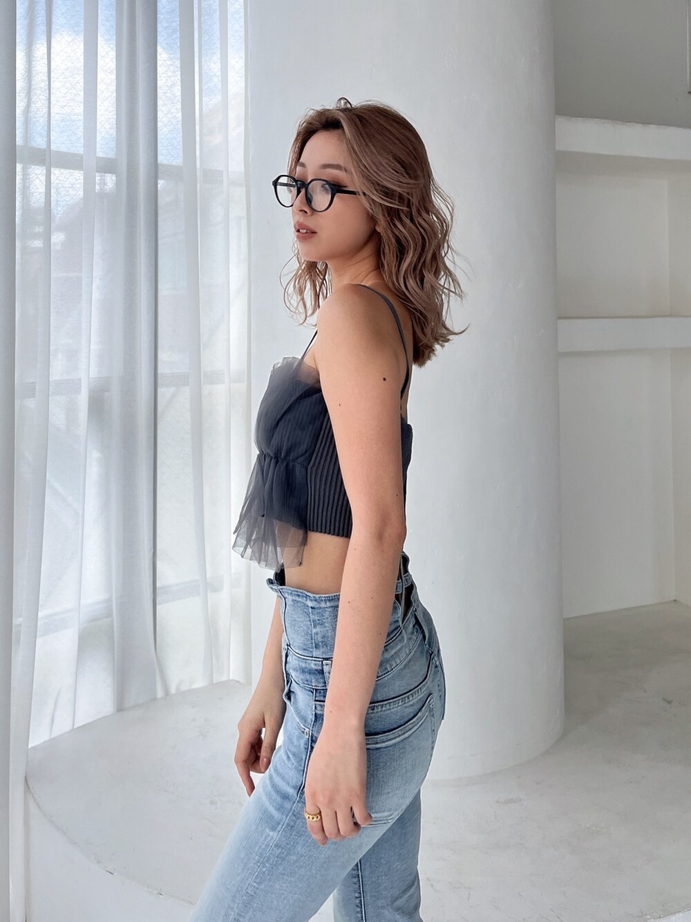 グレー系のキャミソール、ブルー系のデニムパンツ、ブラック系のサンダルを着用したレディースの夏コーディネートの4枚目の写真