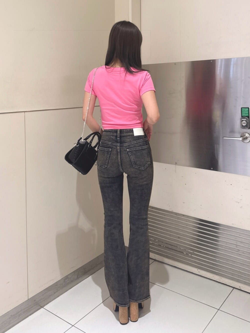 ブラック系のハンドバッグ、ブラック系のサンダル、ブルー系のデニムパンツを着用したレディースの夏コーディネートの3枚目の写真