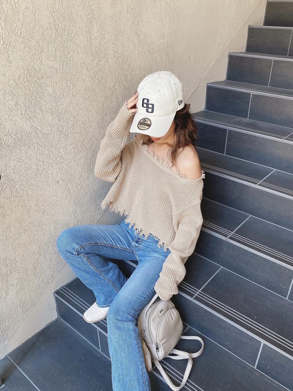 ブルー系のデニムパンツ、ベージュ系のニット/セーター、ホワイト系のキャップを着用したレディースの冬コーディネートの5枚目の写真