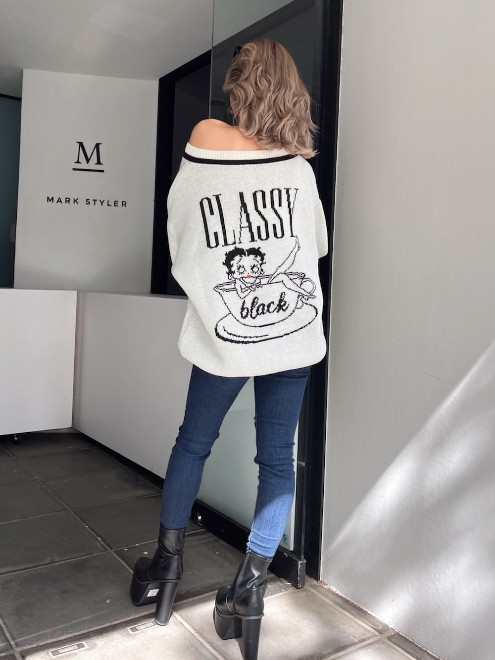 ブラック系のブーツ、ブルー系のデニムパンツ、ホワイト系のニット/セーターを着用したレディースの秋コーディネートの2枚目の写真