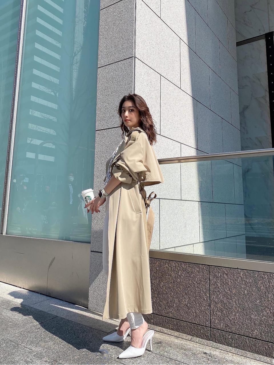 ベージュ系のトレンチコート、ホワイト系のデニムパンツ、ホワイト系のニット/セーターを着用したレディースの春コーディネートの6枚目の写真