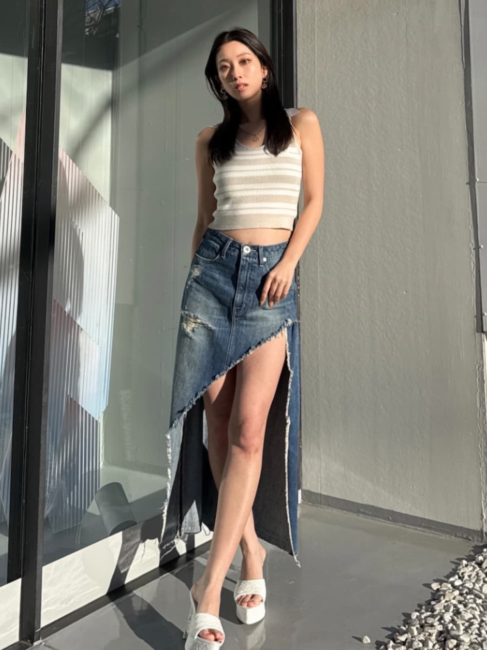 ブルー系のデニムスカート、ベージュ系のニット/セーターを着用したレディースの夏コーディネートの2枚目の写真