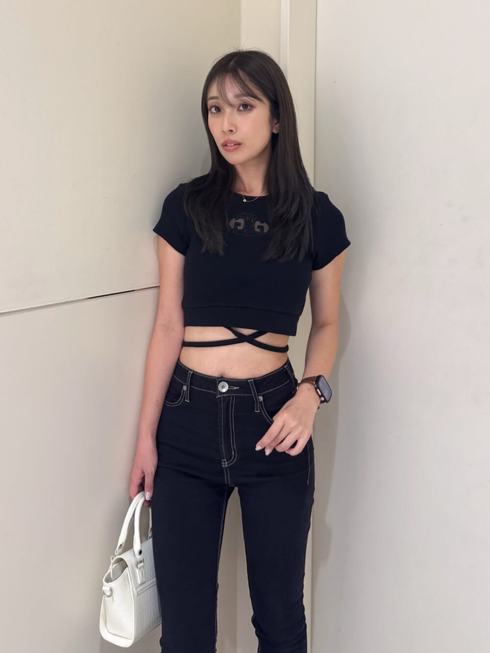 ブラック系のサンダル、ブラック系のハンドバッグ、ブラック系のデニムパンツを着用したレディースの夏コーディネートの4枚目の写真