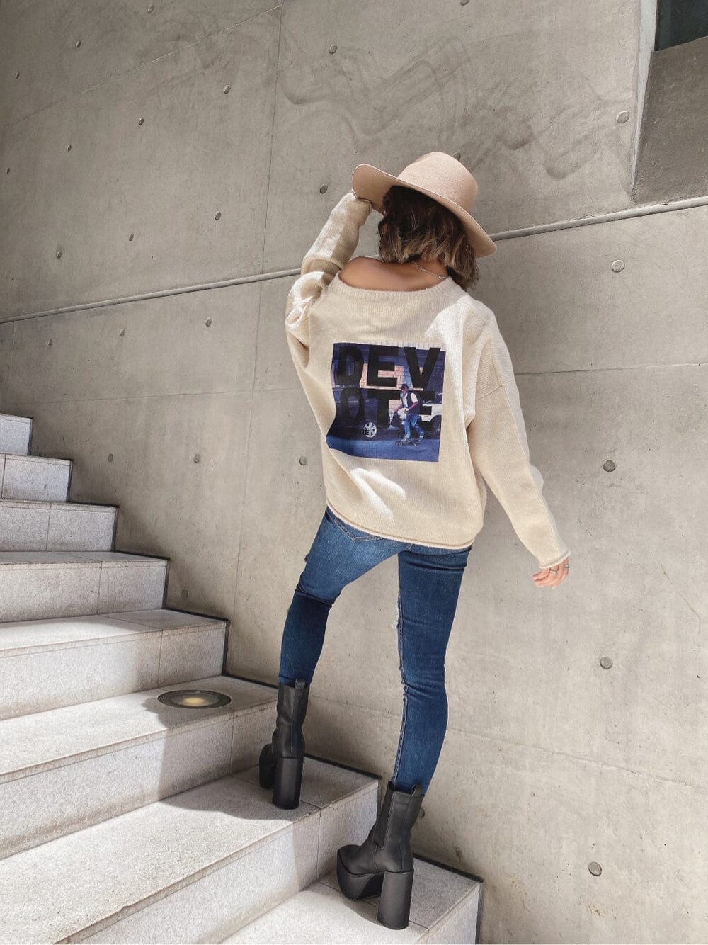 ブラック系のブーツ、ホワイト系のニット/セーター、ブルー系のデニムパンツを着用したレディースの秋コーディネートの2枚目の写真