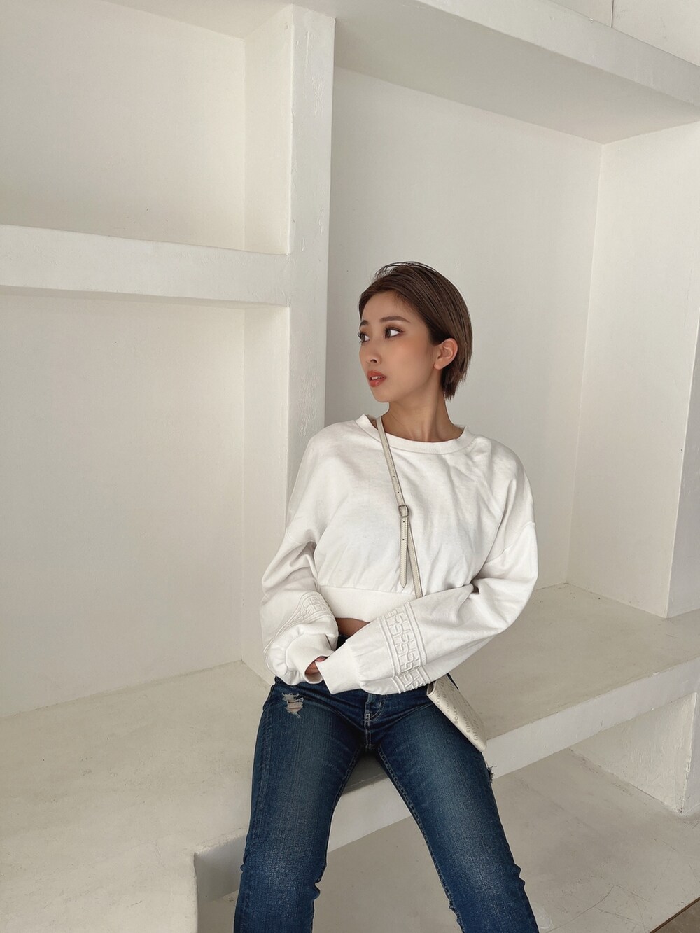 ホワイト系のスウェット、ブルー系のデニムパンツ、ブラック系のパンプスを着用したレディースの冬コーディネートの4枚目の写真