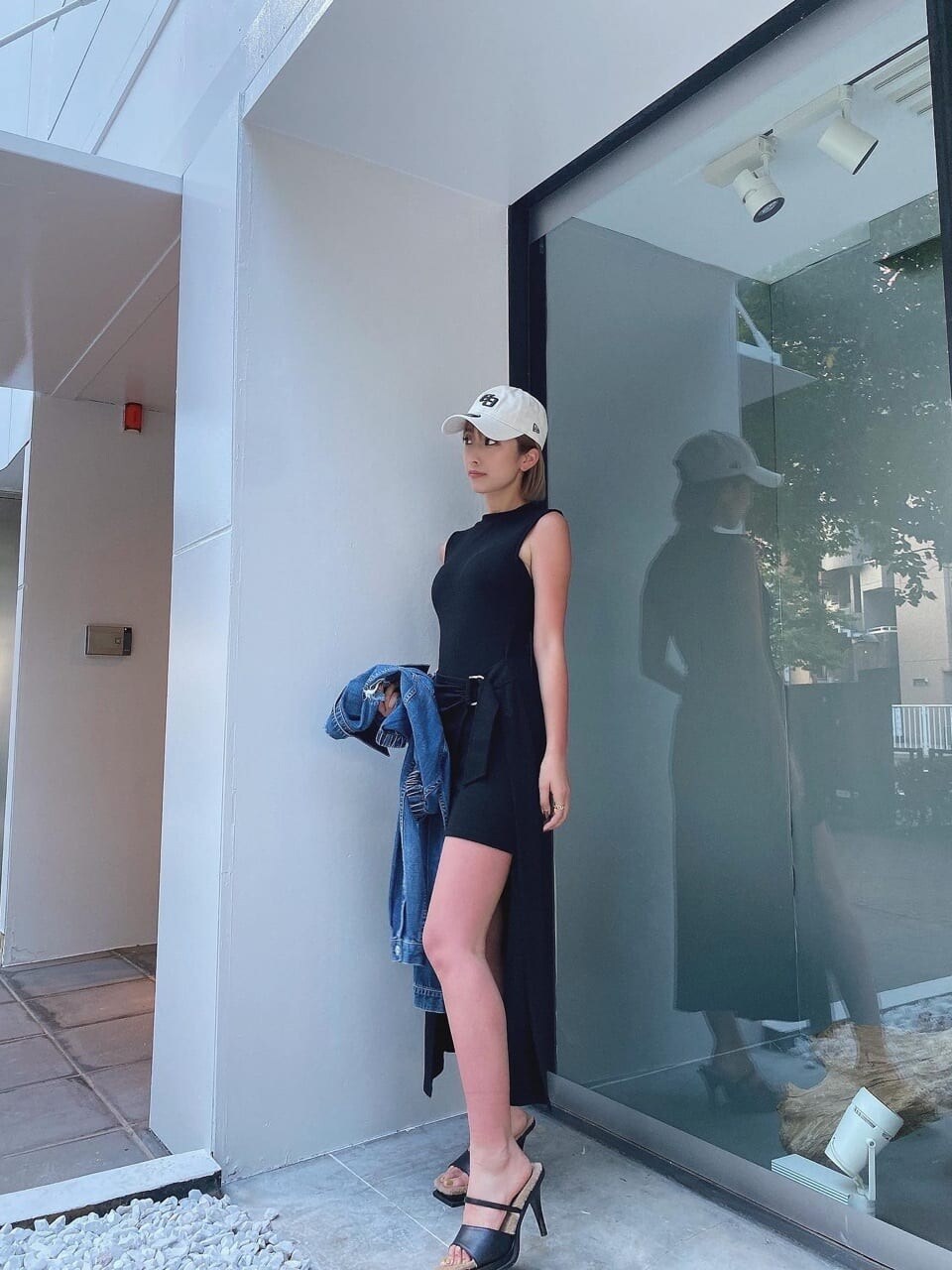 ブラック系のワンピース、ブラック系のサンダル、ホワイト系のキャップを着用したレディースの夏コーディネートの2枚目の写真