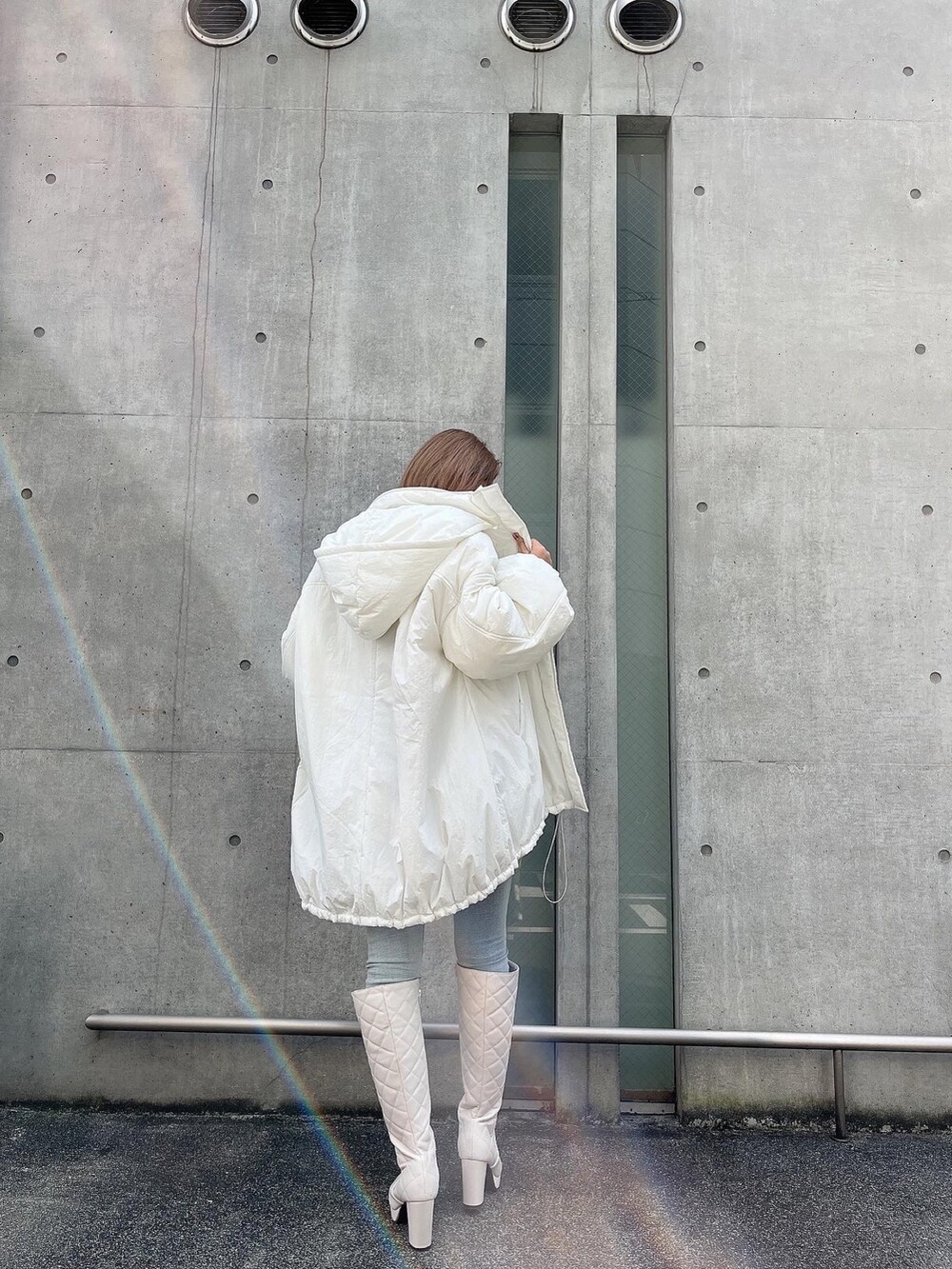 ホワイト系のブルゾン、ホワイト系のスウェット、ブラック系のブーツを着用したレディースの冬コーディネートの2枚目の写真