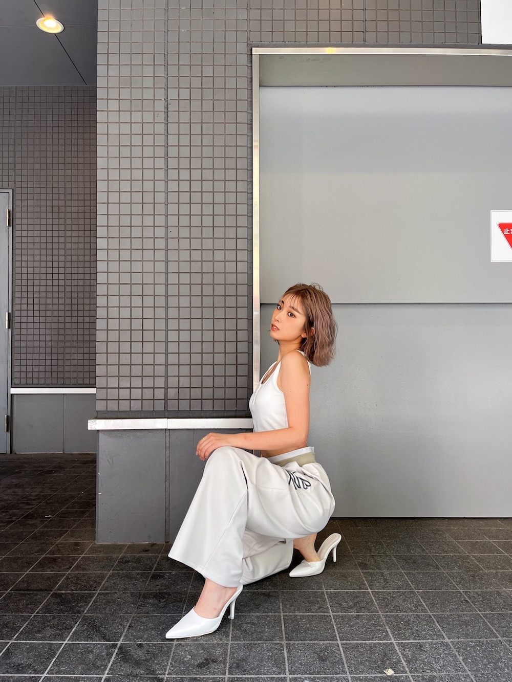 ホワイト系のタンクトップ、ホワイト系のスウェットパンツ、ホワイト系のパンプスを着用したレディースの夏コーディネートの3枚目の写真