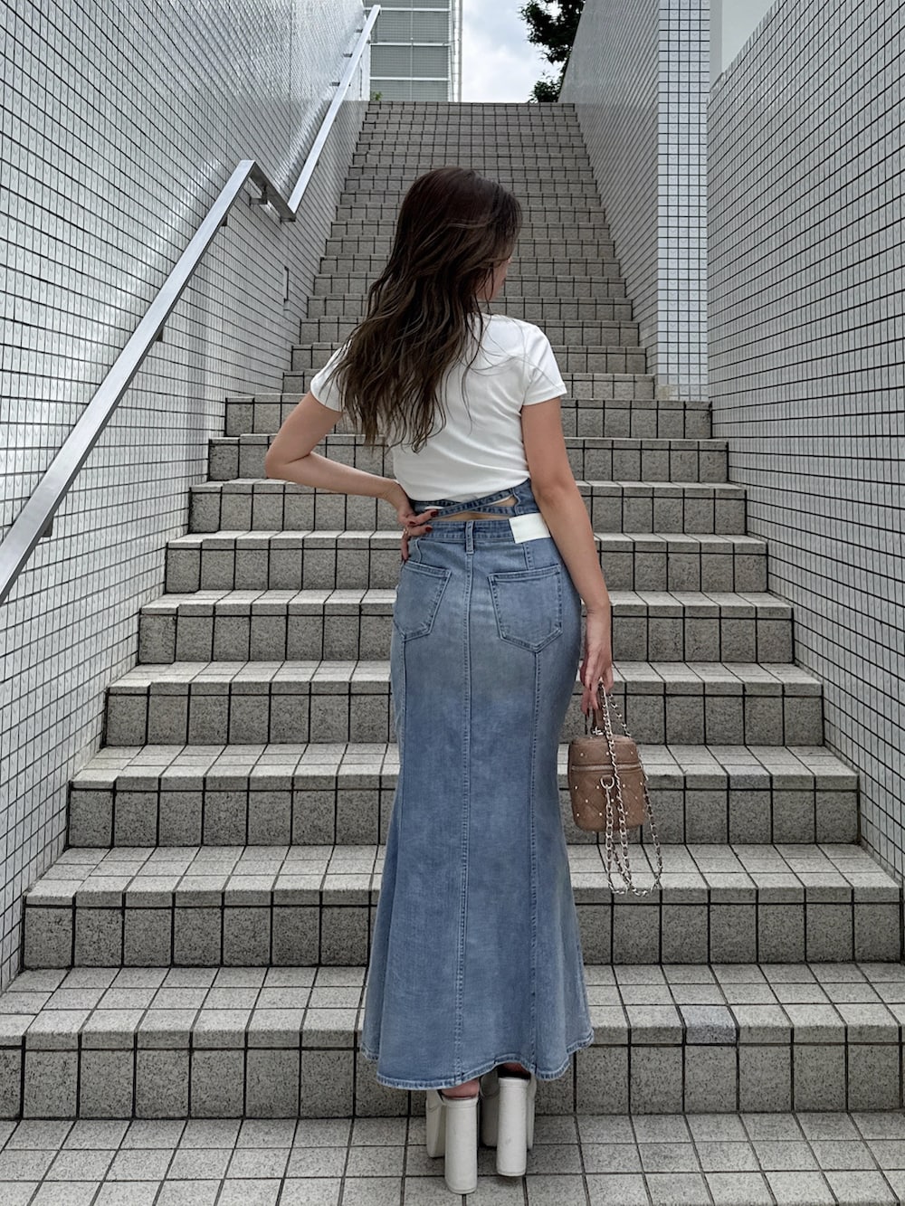 ブルー系のデニムスカート、ホワイト系のTシャツ/カットソー、ホワイト系のサンダルを着用したレディースの秋コーディネートの2枚目の写真