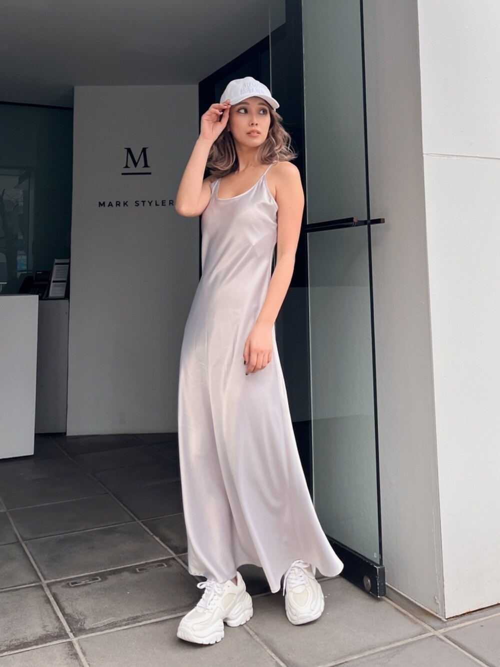 グレー系のワンピース、ホワイト系のキャップを着用したレディースの夏コーディネートの4枚目の写真